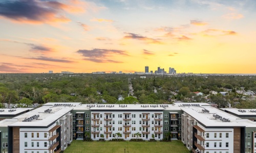 a apartment building with grass and a view of trees and a downtown area at dusk